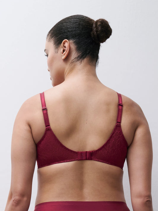 Rear view of a woman wearing a burgundy lace underwire bra against a light gray studio background.