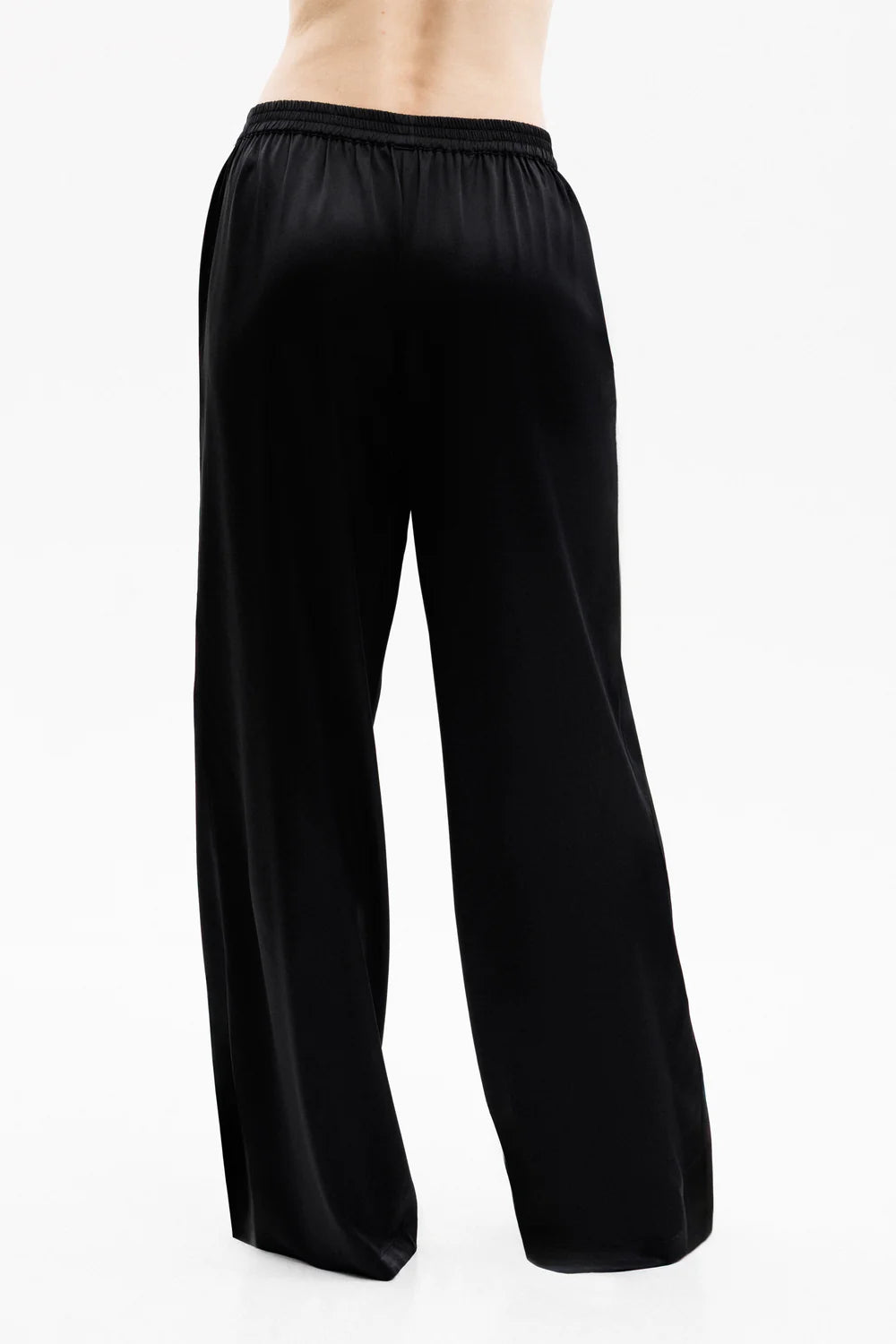 Woman wearing a black silk  pants showing the back