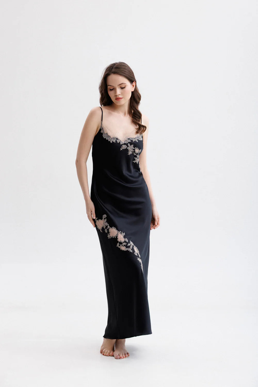 Woman wearing a black silk slip dress with floral embroidery