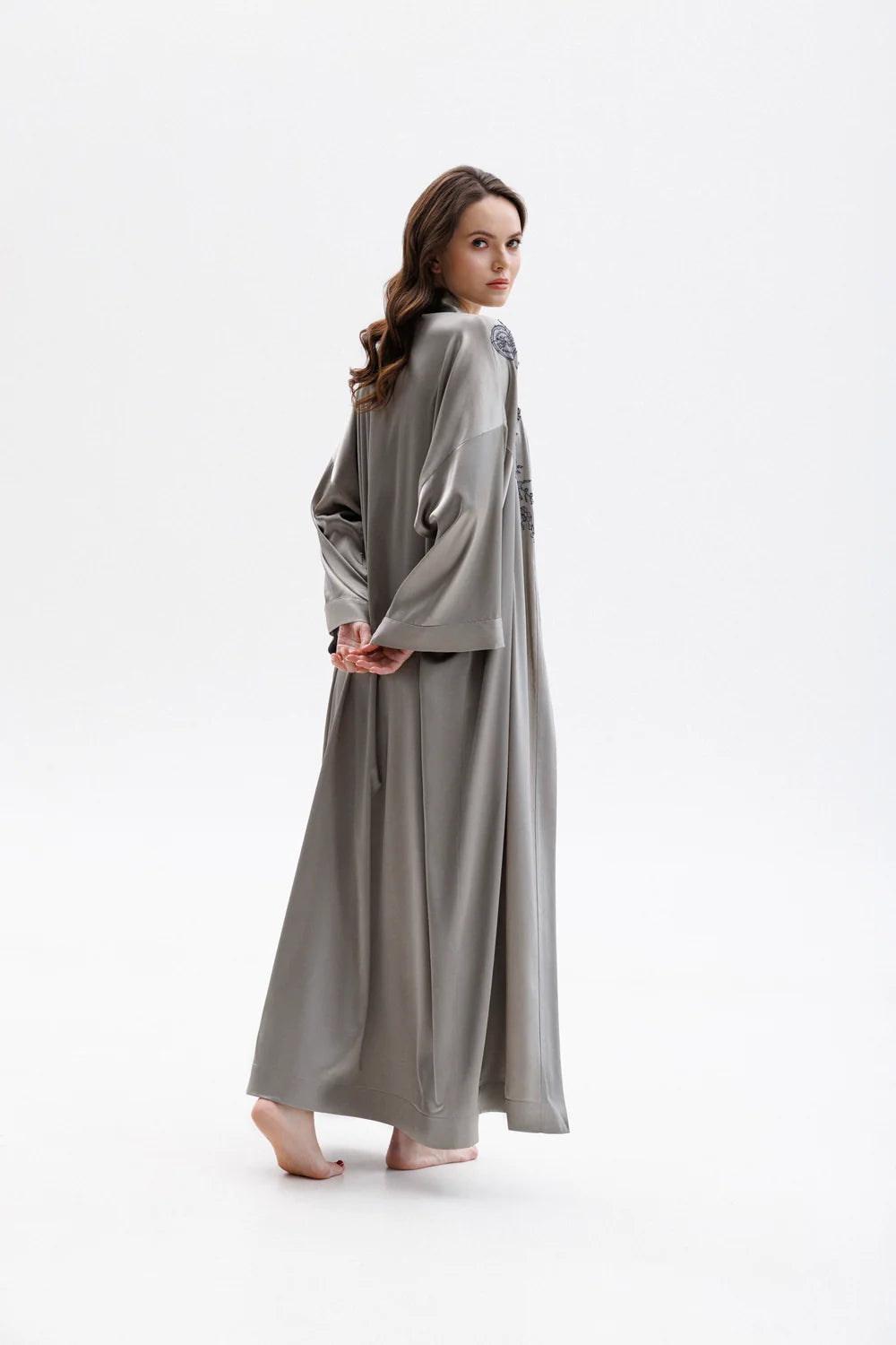 Woman wearing a long gray silk peignoir, showing the back of the full figure