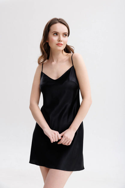 Woman wearing a black silk short slip dress with spaghetti straps